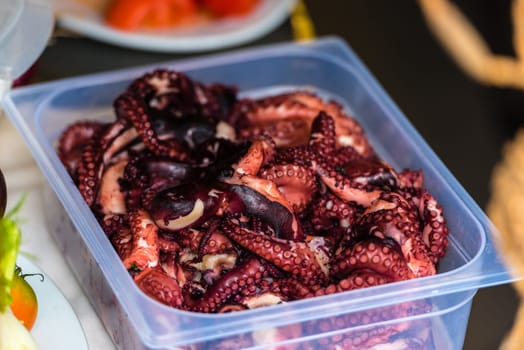 Cooked octopus parts in a box ready for serving in a restaurant