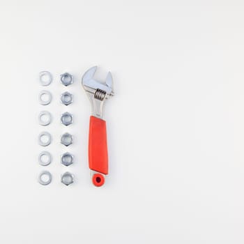 Creative square knolling Flat lay of metal nuts and spanner on white background with copy space. Repair or improvement top view concept.
