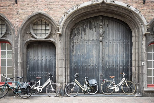 Bicycles leaning against old wooden door at the entrance to house.