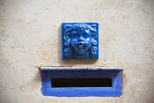 Plaster wall with blue decorative letter slot mailbox. Horizontal shot