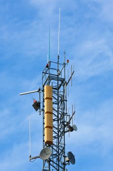 A radio communications tower with dishes against a blue sky