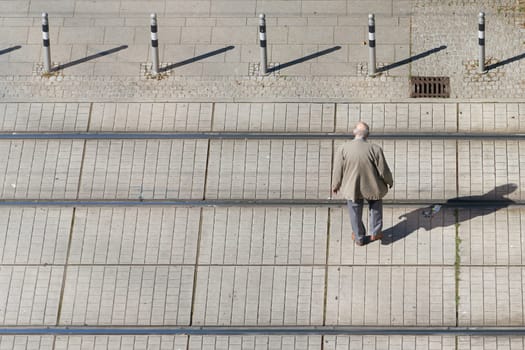 old pensioner in the city center crossing the tracks of a streetcar with text space on the left side