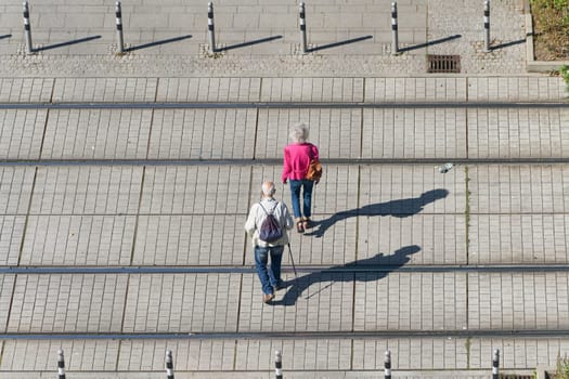 Old pensioner couple crossing the tracks of a streetcar on their way through the city center