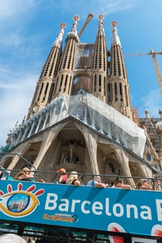 SPAIN, BARCELONA - SEPTEMBER 13: People sitting on a double decker tourist coach in front of The Sagrada Familia Cathedral in Barcelona on September 13, 2015