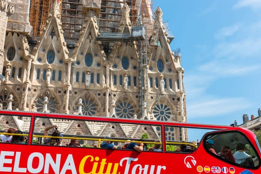 SPAIN, BARCELONA - SEPTEMBER 13: People sitting on a double decker tourist coach in front of The Sagrada Familia Cathedral in Barcelona on September 13, 2015