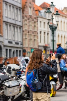 BELGIUM, BRUGES - MAY 22: Woman is taking pictures on the street of Bruges on May 22, 2015