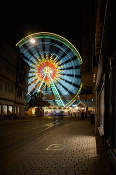 Rotating brightly illuminated Ferris wheel at the Oktoberfest on the cathedral square in Erfurt, Germany