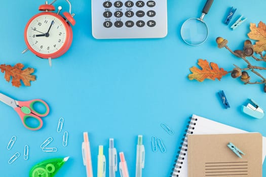 Creative flat lay top view back to school concept with alarm clock, color school and office supplies on bright turquoise paper table frame background with copy space, template for text or design