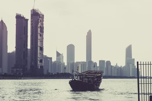 Abu Dhabi buildings skyline with old fishing boat on the front