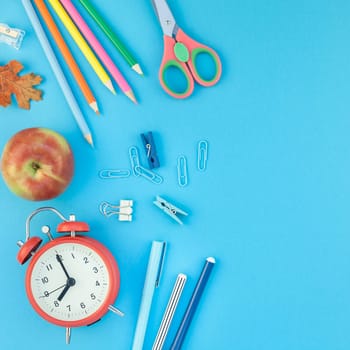 Square Creative flat lay top view back to school concept with alarm clock color school and office supplies on bright turquoise paper table frame background with copy space, template for text or design