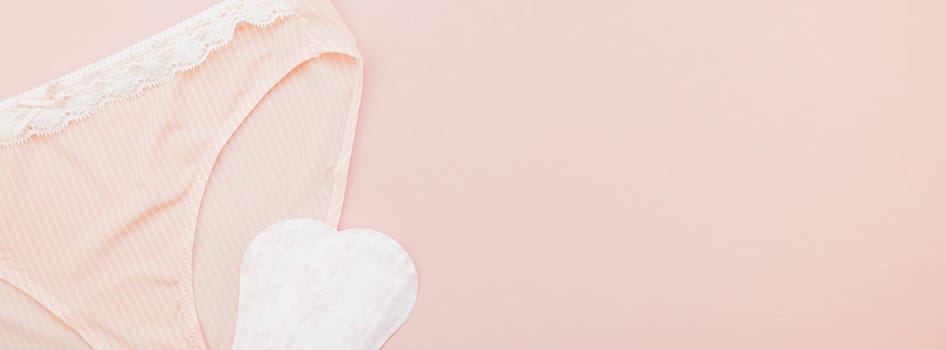 Feminine flat lay set of female panties and pads liners on pastel pink color long wide banner for fashion blog and social media with copy space for text