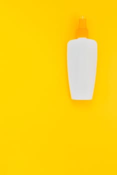 Sunscreen blank bottle mockup on bright yellow paper background. Summer vacations creative flat lay concept template for text
