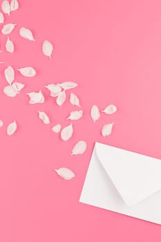 Creative flat lay concept top view of blank letter mock up and apple tree flowers petals on pastel pink background with copy space in minimal style, template for text