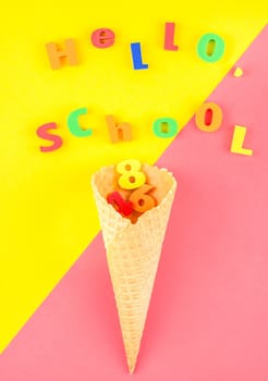 Creative flat lay back to school concept with waffle cone and welcome letters message on bright yellow and pink paper background with copy space, template for text or design