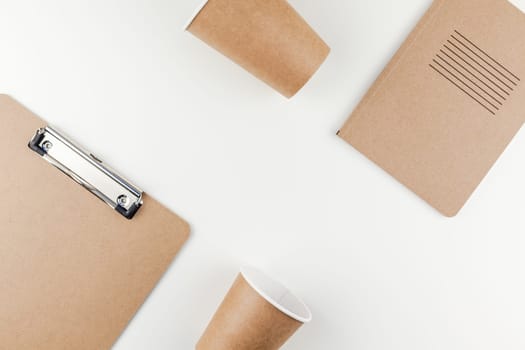 Creative top view flat lay of workspace desk styled recycled brown design office supplies and coffee cups with copy space white table background minimal eco style. Concept of environmental protection
