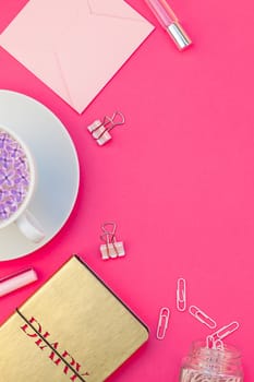 Creative top view flat lay of workspace desk styled design office supplies and cup of tea with copy space on a bright pink color paper background minimal style. Template for feminine blog social media