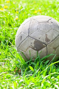 Old soccer ball forgotten in the green grass field. The football concept