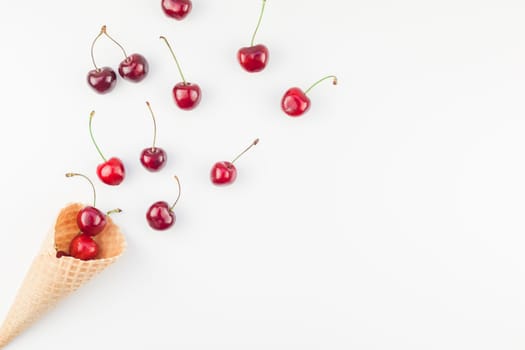 Creative top view of ripe cherries in a waffle cone with copy space isolated on white background in minimal style. Concept of summer fun and healthy eating. Template for your text or design.