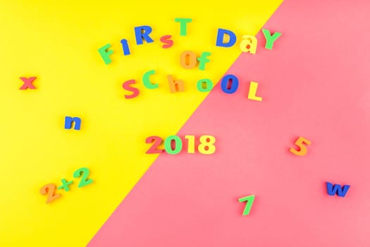 Creative flat lay back to school concept with welcome letters message on bright yellow and pink paper background with copy space, template for text or design
