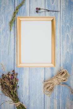 Top view of autumn orange pumpkins and dry flowers with grass thanksgiving background over blue toned wooden table with golden frame mock up and copy space in rustic style, template for text