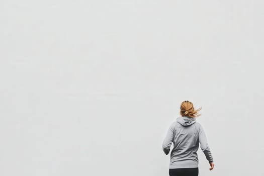 A jogger moves energetically in the morning light, their hair flowing behind them. The backdrop is a stark, clean white, emphasizing the runners motion and dedication to fitness.