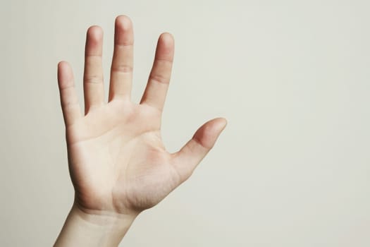 A hand with fingers spread wide is extended outward, showcasing an open palm against a simple, clean background. The image conveys a sense of openness and invitation, captured in soft lighting.