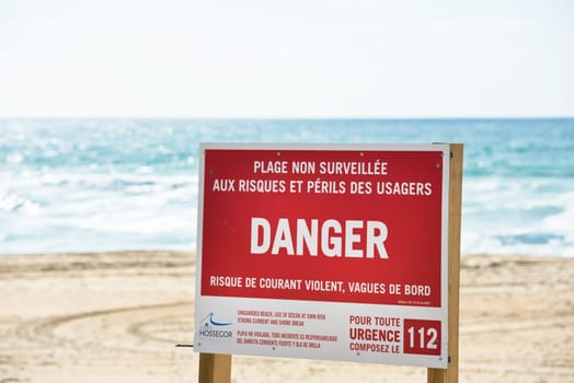 FRANCE, ONDRES - SEPTEMBER 18: Red danger sign on an ocean beach with waves on the background on September 18, 2015
