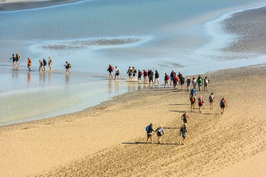 FRANCE, MONT SAINT MICHEL - SEPTEMBER 26: View from walls of Mont Saint Michel on the bay during the low tide with groups of tourists walking. France on September 26, 2015