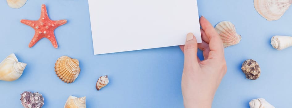 Creative long wide banner flat lay concept of summer travel vacations. Top view of seashells and starfish on pastel blue background with postcard mock up and copy space in minimal style, template
