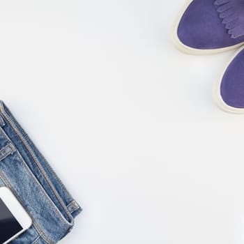 Square Flat lay of suede shoes, blue jeans and smartphoneon white background with copy space. Overhead view of woman casual outfit. Trendy hipster look top view