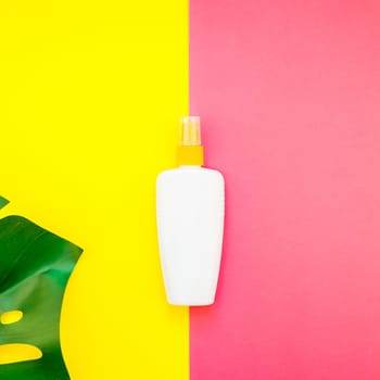 Tropical jungle palm monstera leaves and sunscreen blank bottle mockup on bright square yellow and pink duotone paper background. Summer vacations creative flat lay concept template for text