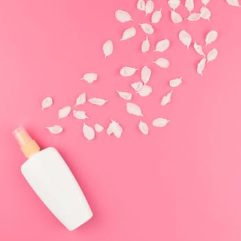 Flat lay set of sunscreen blank bottle mockup and white flowers petals on pastel pink square color background for blog and social media with copy space for text