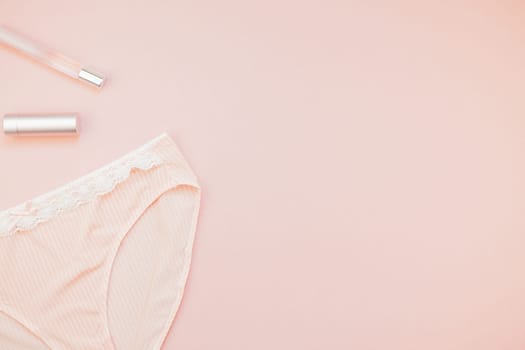 Feminine flat lay set of female panties and accessories, perfumes, lipstick on pastel pink color background for fashion blog and social media with copy space for text