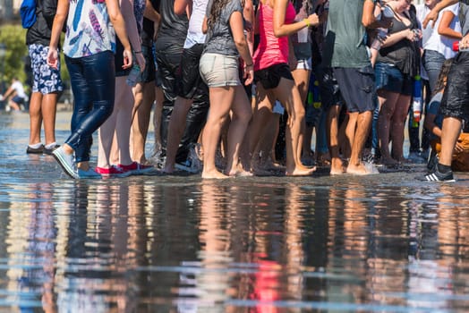 People having fun in a mirror fountain in front of Place de la Bourse in Bordeaux, France