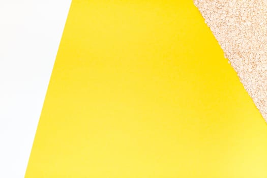 Creative flat lay concept top view of oatmeal flakes for healthy and vegetarian organic food for breakfast on a bright yellow color paper background with copy space in minimal style, template for text