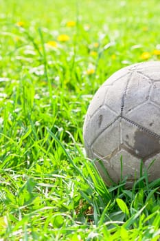 Old soccer ball forgotten in the green grass field. The football concept