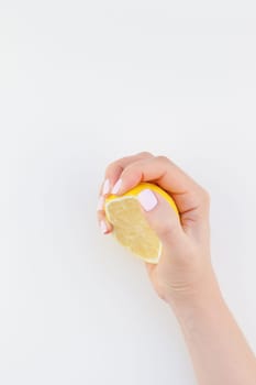 Woman hand with pastel manicure polish holding a half of lemon isolated on white background copy space minimalism style. Template for feminine social media. Healthy eating concept