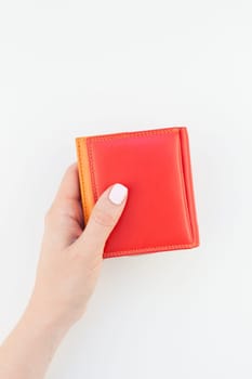 Woman hand with pastel manicure polish holding bright red leather wallet isolated on white background with copy space in minimalism style. Template for feminine beauty blog social financial media