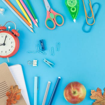 Square Creative flat lay top view back to school concept with alarm clock color school and office supplies on bright turquoise paper table frame background with copy space, template for text or design