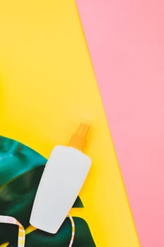 Tropical jungle palm monstera leaves, sunglasses, sunscreen blank bottle mockup and woman's swimsuit top on bright color paper background. Summer vacations creative flat lay concept template for text