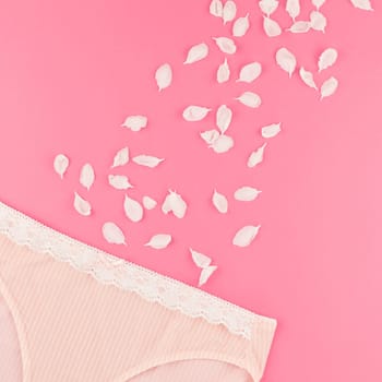 Feminine flat lay set of female panties and white flowers petals on pastel pink square color background for fashion blog and social media with copy space for text