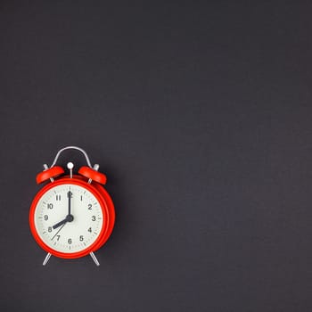 Concept image of a red vintage alarm clock with eight o clock on square dark black color paper background with copy space in minimal style, template for text
