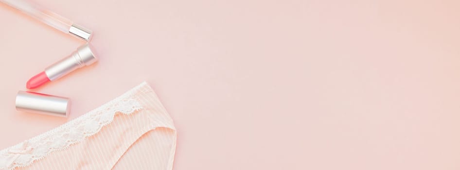 Feminine flat lay set of female panties and accessories, perfumes and lipstick on pastel pink color long wide banner for fashion blog and social media with copy space for text