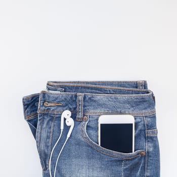 Square Flat lay of blue jeans and smartphone headphones isolated on white background with copy space. Overhead view of woman casual outfit. Trendy hipster look top view