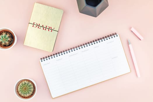 Top view flat lay of workspace desk styled design office supplies and cactuses succulents with copy space millennial pink color paper background minimal style. Template for feminine blog social media