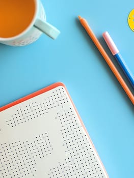 A creative workspace featuring a mug and dotted notebook on a blue surface, ideal for inspiration and planning.