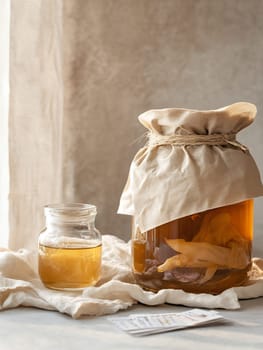 A jar of kombucha with a cloth cover sits in a sunlit room, illustrating the natural process of fermentation with copy space.