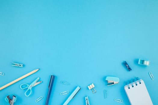 Top view flat lay of workspace desk styled design school and office supplies with copy space turquoise blue color paper background minimal style. Template for feminine blog social media
