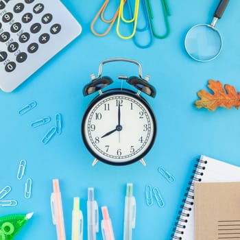 Square Creative flat lay top view back to school concept with alarm clock color school and office supplies on bright turquoise paper table frame background with copy space, template for text or design