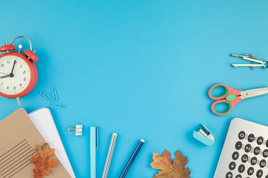 Creative flat lay top view back to school concept with alarm clock, color school and office supplies on bright turquoise paper table frame background with copy space, template for text or design